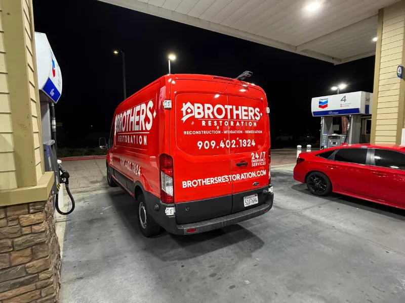 Red Brothers Restoration van at a gas station at night.