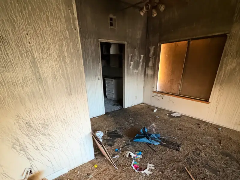 Fire-damaged, smoke-stained room with debris on the floor.
