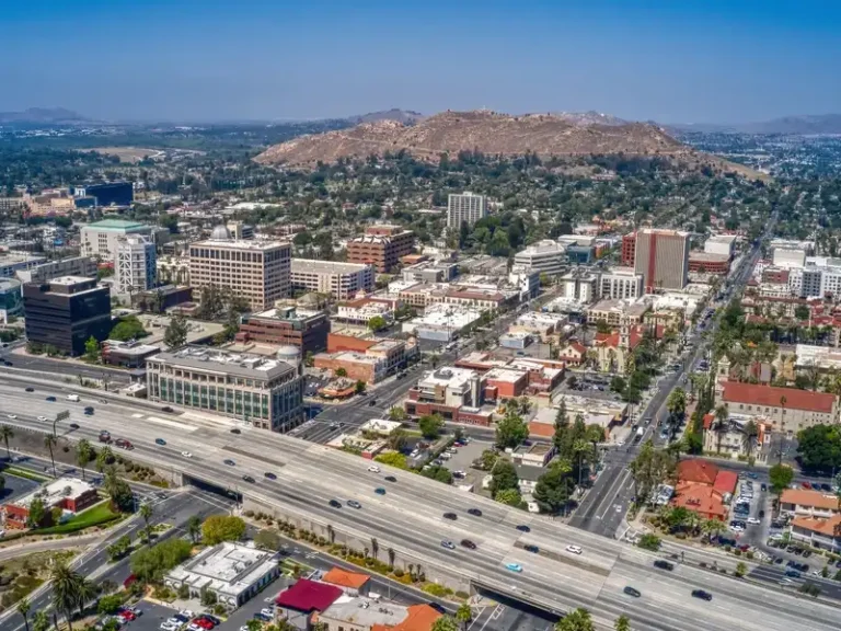 Aerial view of a city with a freeway and hills in the background.