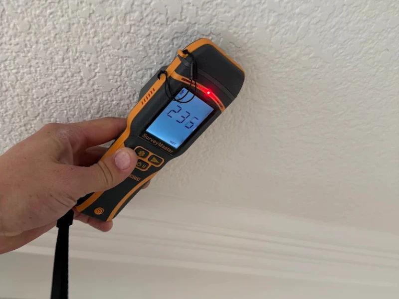 Handheld stud finder scanning a wall.