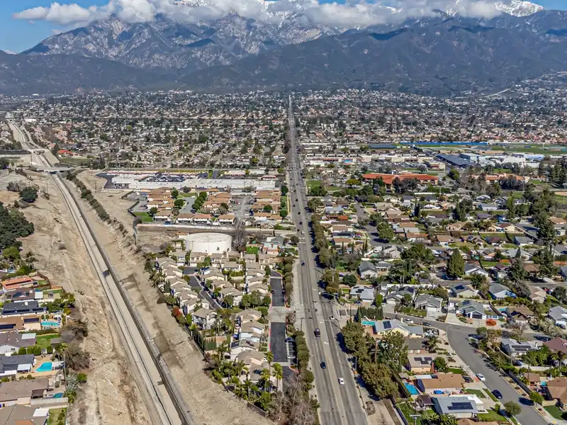 Aerial view of a suburban city with a long straight road and mountains in the background.
