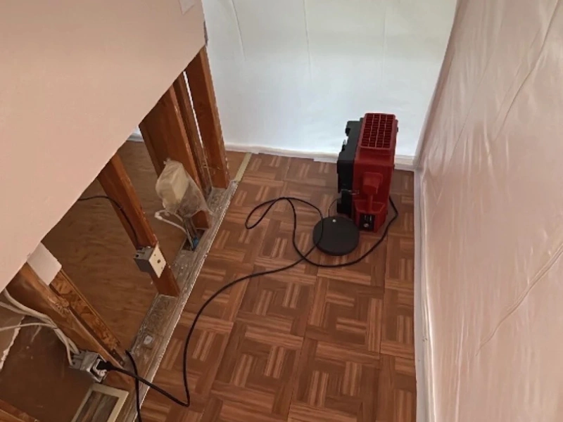 Red dehumidifier in a stripped room with exposed wall studs.